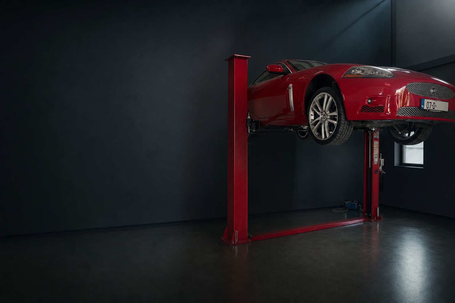 Red Jaguar XKR raised on a Pacini two post car lift